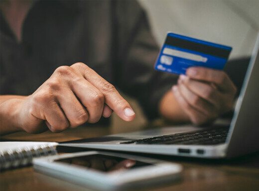 Person holding a credit card and typing on a computer